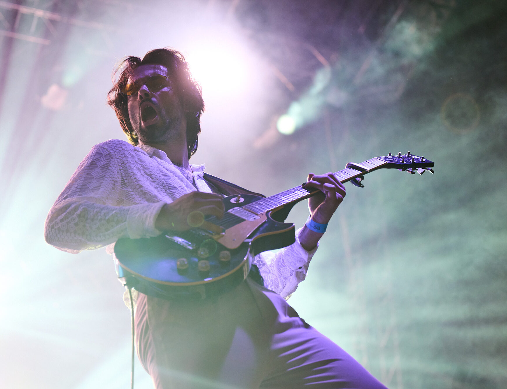 Slovenian indie rock music band Joker Out preformed in city Maribor. The guitarist of the band is playing on the guitar illuminated by concert lights.