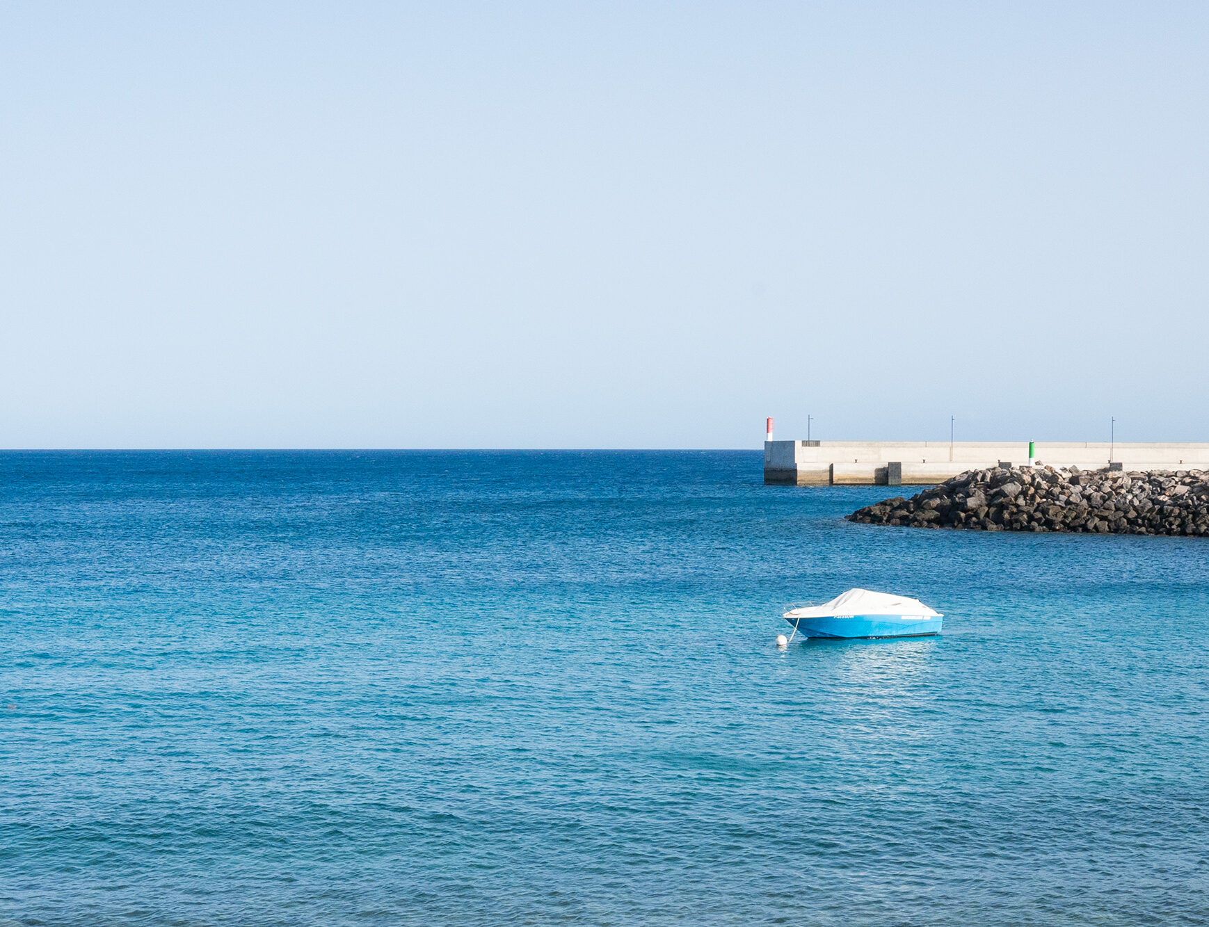 Peaceful island life in Lanzarote. A small boat moving in the Atlantic Ocean.