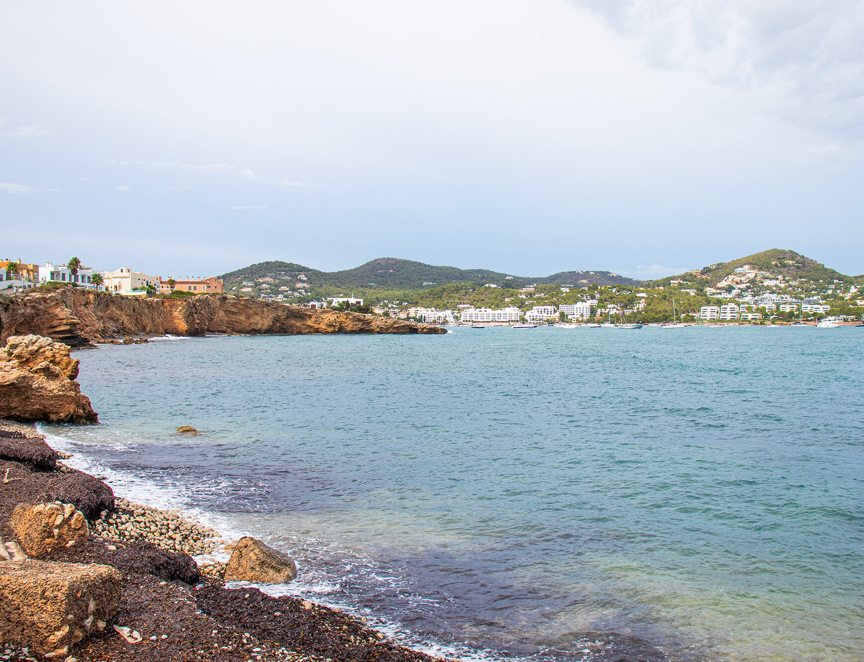 Beach sea view in Balearic island, Ibiza. Beautiful vivid colors and buildings in the background.